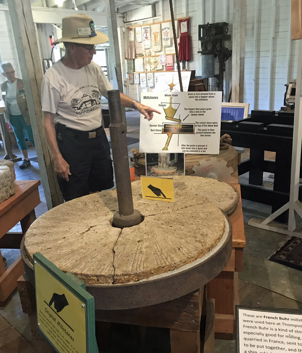 A docent explains the way mill stones were used.  The stones are 3 feet across and grooved for grinding the grain.
