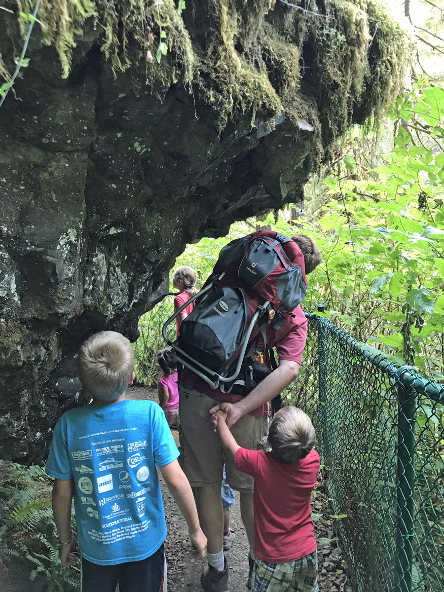 Our family walks under overhanging rocks during a hike to North Falls.